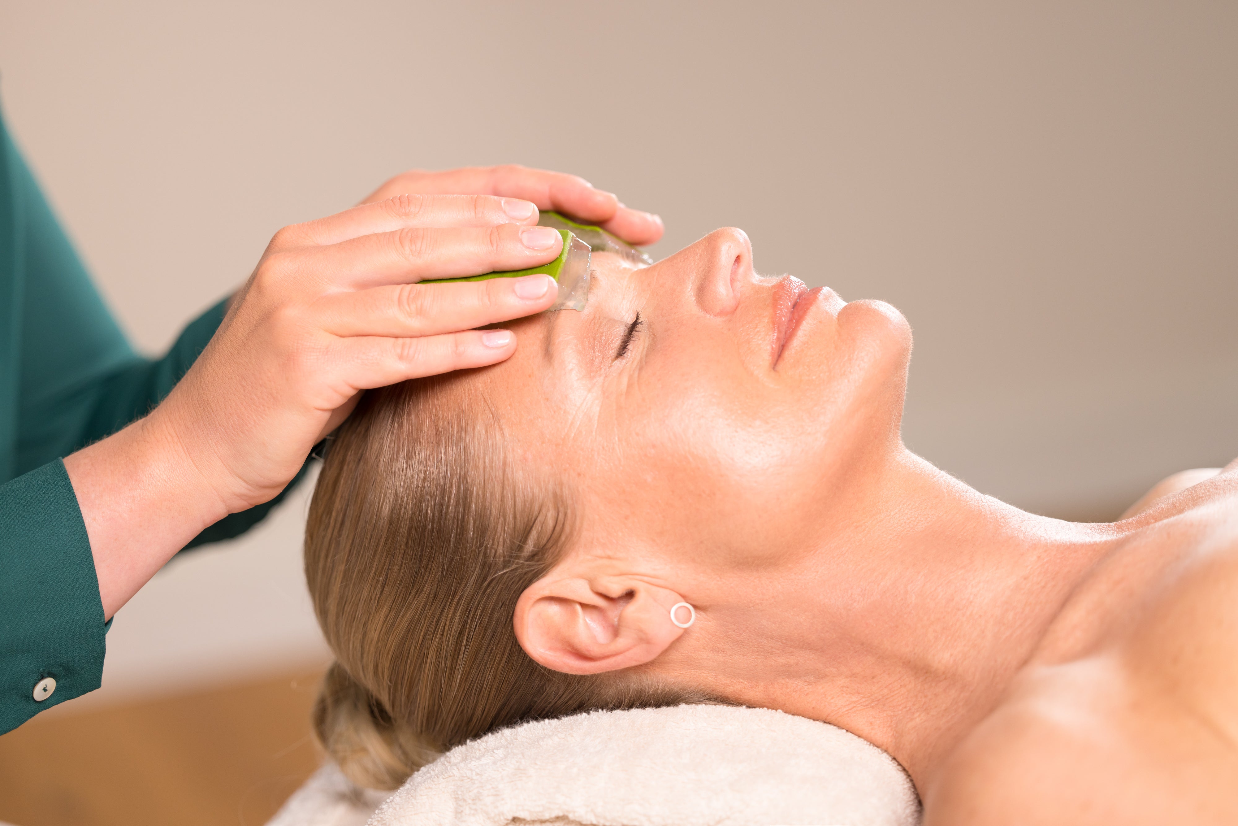 Frau wird im Gesicht mit Aloe Vera Frischblatt behandelt